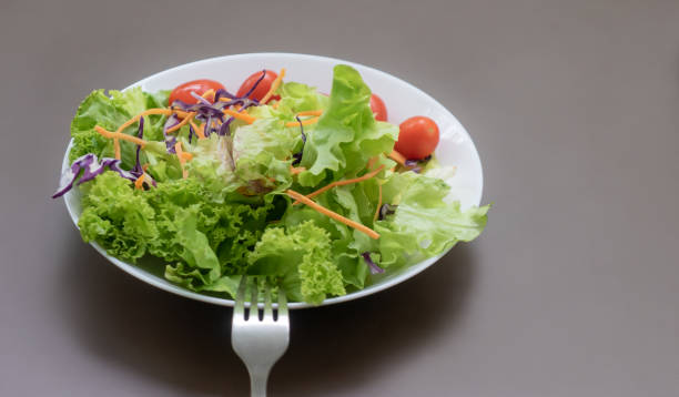 istock Green fresh vegetable salad on white place and brown table 1170254450