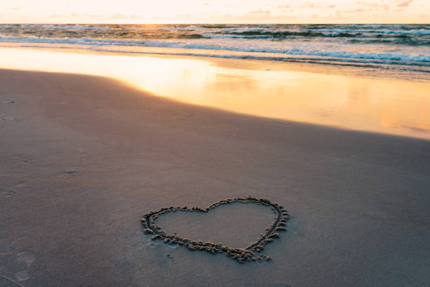 istock heart shape on a sandy seaside beach drawn with a wooden stick at sunset 1170256461