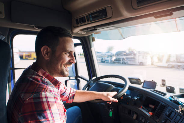Truck driver job. Middle aged trucker driving truck. Professional middle aged truck driver in casual clothes driving truck vehicle going for a long transportation route. truck driver stock pictures, royalty-free photos & images