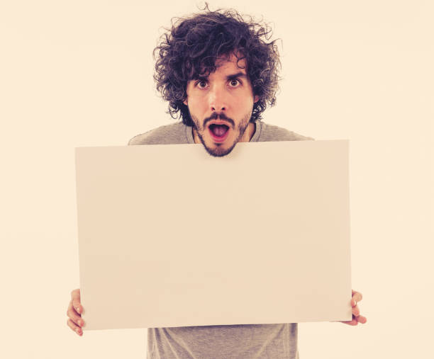 istock Funny and good looking man showing and pointing at blank board with copy space for advertisement text. Looking happy surprised and shocked at great ad. In marketing concept. 1170262140
