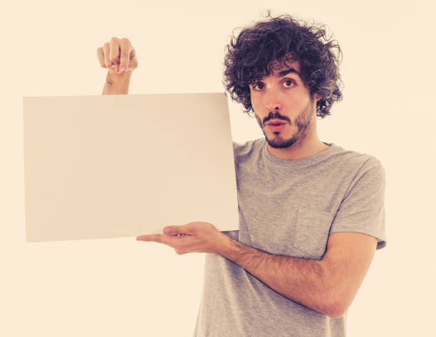 istock Funny and good looking man showing and pointing at blank board with copy space for advertisement text. Looking happy surprised and shocked at great ad. In marketing concept. 1170262157