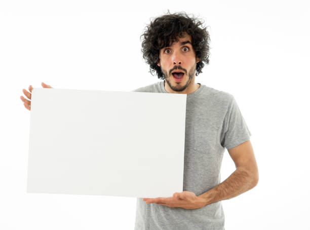 istock Funny and attractive man showing blank poster with copy space for text looking excited as it shows a great product or amazing sale or great advertisement. studio shot. Marketing concept. 1170262183
