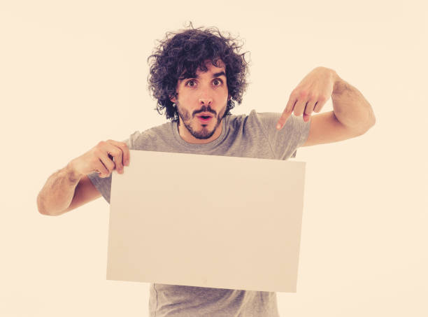istock Funny and attractive man showing blank poster with copy space for text looking excited as it shows a great product or amazing sale or great advertisement. studio shot. Marketing concept. 1170262188
