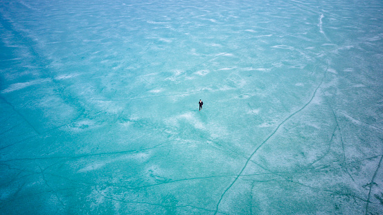 Man walking on Surface of Frozen Lake from drone aerial view at Pangong Lake or Pangong Tso, Tso moriri – Nubra, India. Abstract concept of Cold winter, peaceful and freedom.