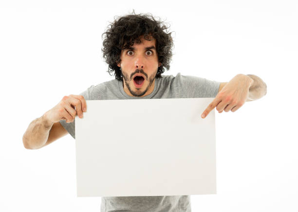 istock Funny and attractive man showing blank poster with copy space for text looking excited as it shows a great product or amazing sale or great advertisement. studio shot. Marketing concept. 1170262233