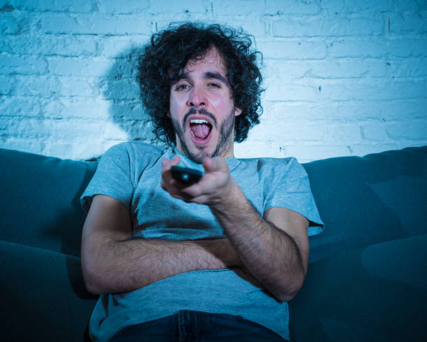 istock Bored man watching sitcom or series falling asleep on sofa late at night. young male zapping and changing TV channels looking for show or movie killing time at night feeling restless 1170262278