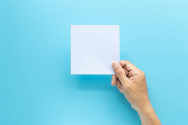 istock man hand holding blank card paper sheet isolated on blue background with copy space. 1170262607