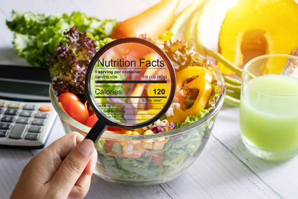 nutritional information concept. hand use the magnifying glass to zoom in to see the details of the nutrition facts from food , salad bowl - portion imagens e fotografias de stock