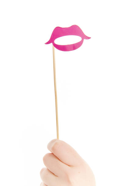 A hand holds up a party mask or prop shaped like  bright pink lips.