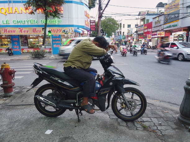 Asian motor taxi (Xe Om) waiting for passenger at Danang ,Vietnam Danang, Vietnam - August 23, 2019: Asian motor taxi (Xe Om in Vietnamese) waiting for passenger in crossroads at Danang ,Vietnam. vietnamese man taxi motorbike driver stock pictures, royalty-free photos & images