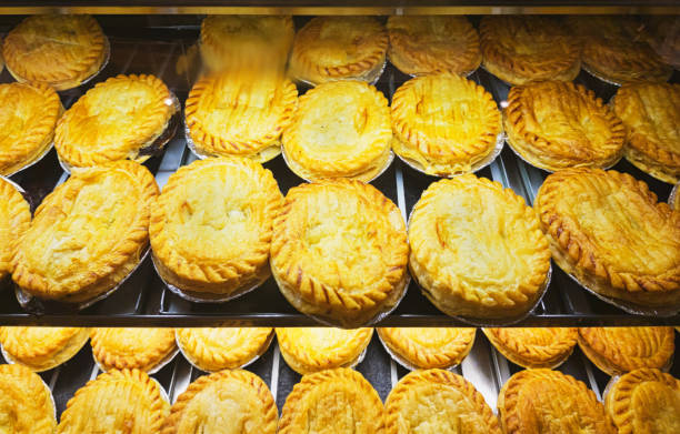 Many meat pies on display in a bakery warmer