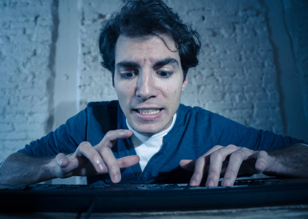 istock Addict young man alone at night on computer laptop feeling stressed and overwhelmed trying to finish work or winning online game or gambling. In workaholic and internet technology addiction. 1170265276