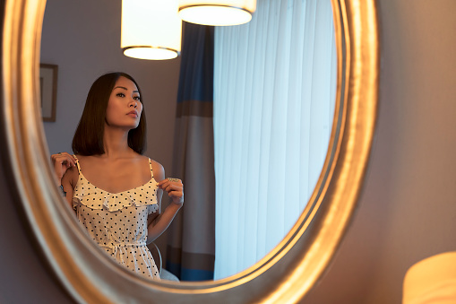 Asian woman checking herself out in a mirror, make-up with beauty products