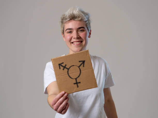 Good looking happy and proud trans teenager holding the symbol of the transgender drawn on a cardboard plate. Conceptual image of gender identity and diversity. Human rights and equality campaign. Good looking happy and proud trans teenager holding the symbol of the transgender drawn on a cardboard plate. Conceptual image of gender identity and diversity. Human rights and equality campaign. non binary gender stock pictures, royalty-free photos & images