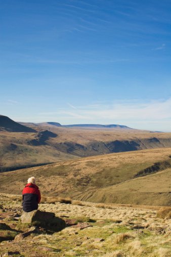 An unrecognisable woman looks out over the Brecon Beacons from half way up Pen Y Fan.  On a clear winters day the view is astounding for miles around.