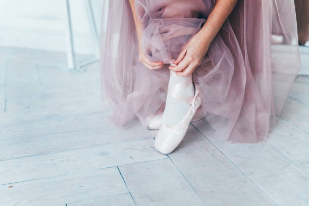 istock Ballerina hands puts pointe shoes on leg in dance class 1170268783