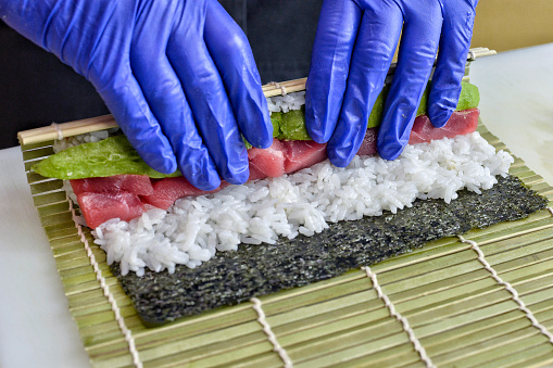 Close-up of the hands of a chef making sushi.