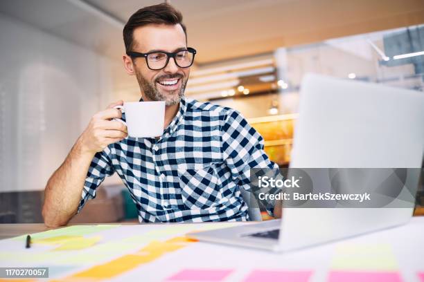 Glücklicher Geschäftsmann Trinken Kaffee Arbeiten Auf Seinem Laptop Von Zu Hause Büro Stockfoto und mehr Bilder von Kaffee - Getränk