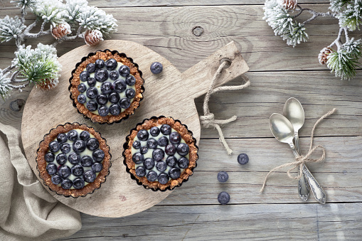 Winter blueberry tarts on wooden table decorated with pine twigs