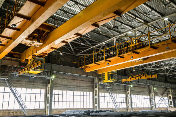 Two yellow overhead cranes in engineering plant shop. Industrial metalwork production hall and warehousing workshop. stock photo