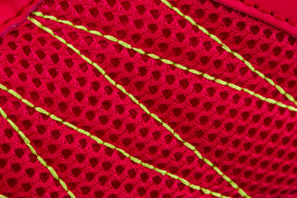 Fragment of red sneaker fabric. The texture of the material of sports shoes Fragment of red sneaker fabric. The texture of the material of sports shoes multi colored woven macro mesh stock pictures, royalty-free photos & images