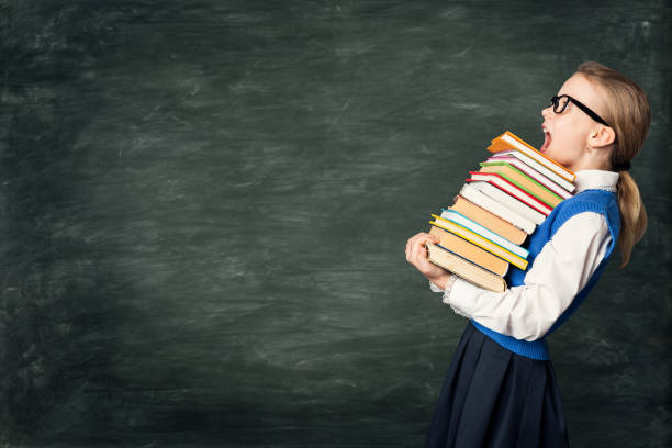 Amazed School Girl Holding Many Books, Astonished Strong Child on Blackboard, Hard Education Amazed School Girl Holding Many Books, Astonished Strong Child Side View over Blackboard Background, Hard Education concept blackboard child shock screaming stock pictures, royalty-free photos & images