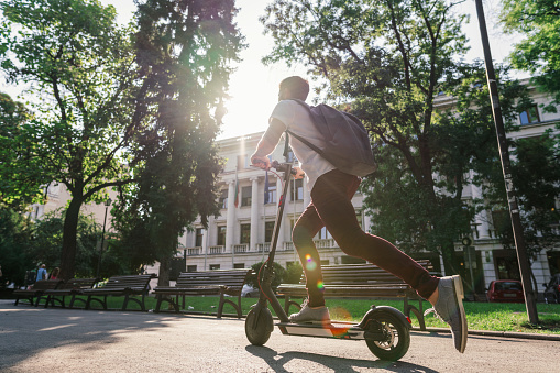 Hombre montando e-scooter a través del parque de la ciudad photo