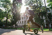 Man riding e-scooter through the city park