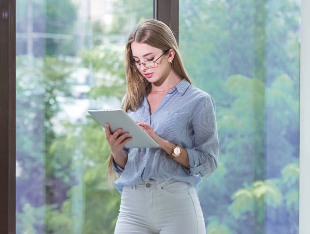 istock Beautiful young female employee with a tablet computer in her hands working in a spacious bright office 1170280718