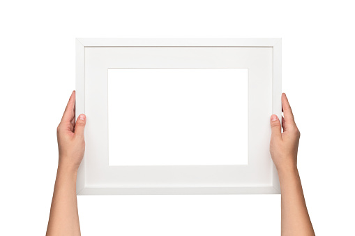 Woman hanging a frame on the wall. Empty white frame template.