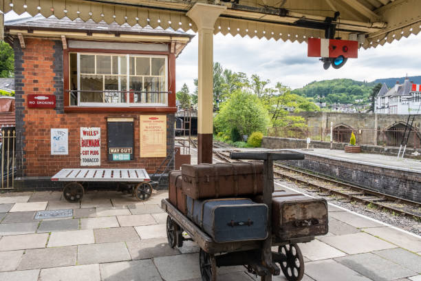 Llangollen, Denbeighshire, Wales - 22nd May 2019. Luggage trunks wait on a trolley by the signal box on the platform of Llangollen Railways, a heritage railway in north east Wales