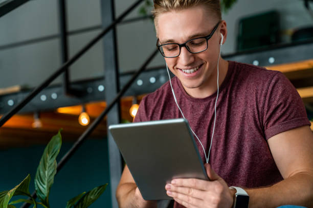 istock Young smiling man using digital tablet and headphones in the office 1170289424