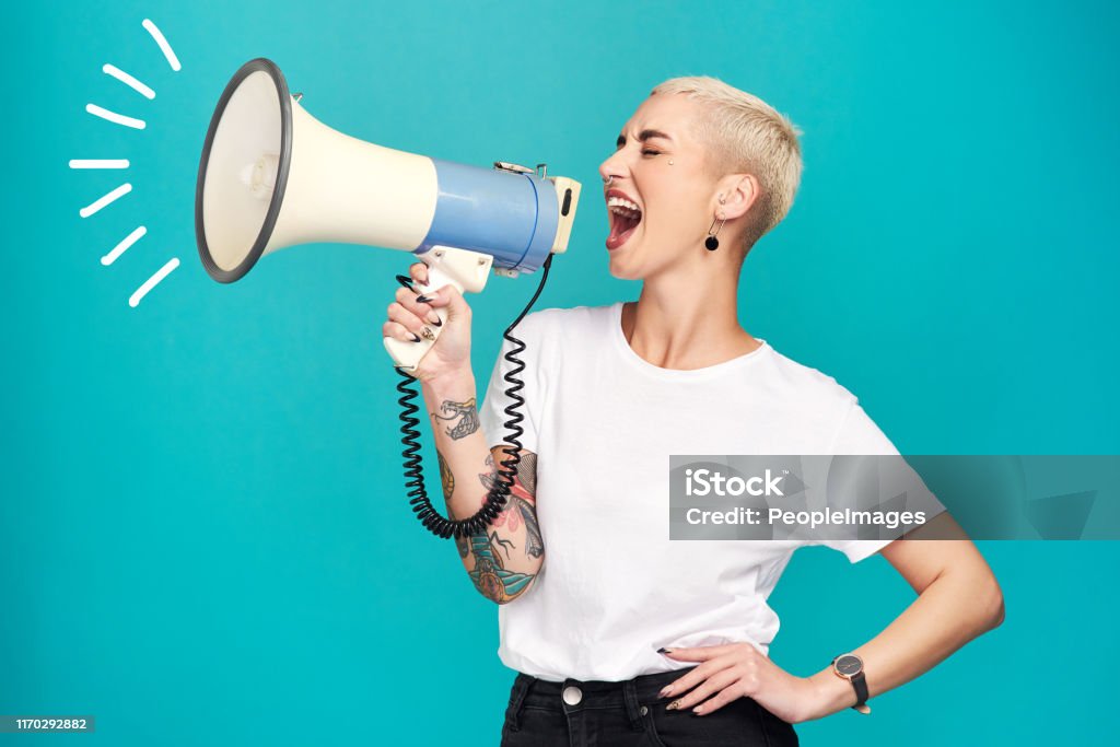 I will not be silenced!! Studio shot of a young woman using a megaphone against a turquoise background Megaphone Stock Photo