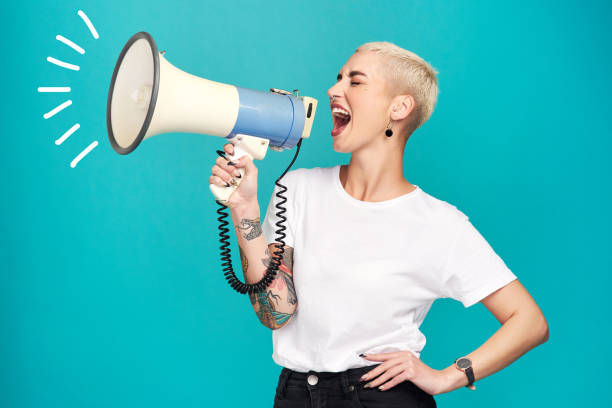 I will not be silenced!! Studio shot of a young woman using a megaphone against a turquoise background screaming stock pictures, royalty-free photos & images