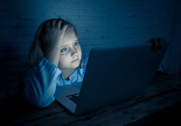 Scared sad girl bullied online on laptop suffering cyber bullying harassment. School girl humiliated on the internet by classmates feeling desperate and intimidated. Children victim of bullying. stock photo