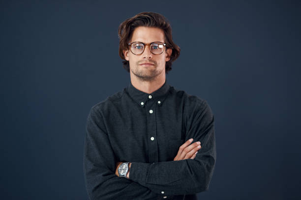 Portrait of a handsome young businessman posing with his arms folded against a dark background