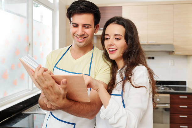 istock Cheerful couple in aprons reading cooking book 1170297847