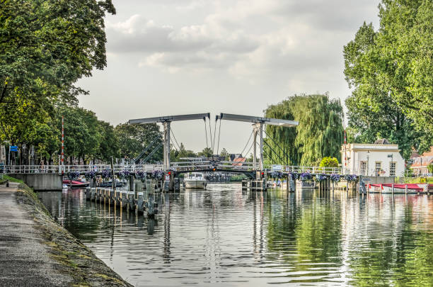 Weesp, The Netherlands, August 18, 2019: view from the quay towards the drawbridge across the treelined river Vecht on a summer evening