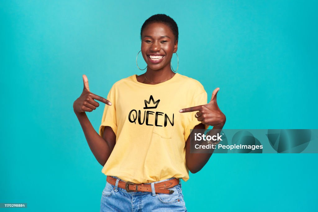 The name says it all Studio shot of a confident young woman wearing a t shirt with “queen” on it against a turquoise background Women Stock Photo