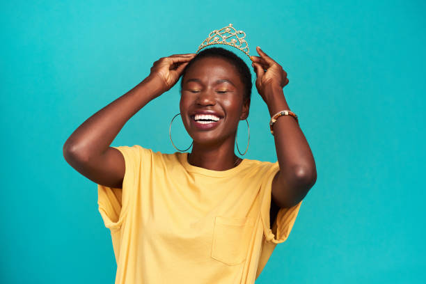 Princess? Try queen Studio shot of a young woman putting a crown her head against a turquoise background royal person photos stock pictures, royalty-free photos & images