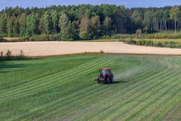 istock Farming in Finland: red tractor mowing green field 1170301057