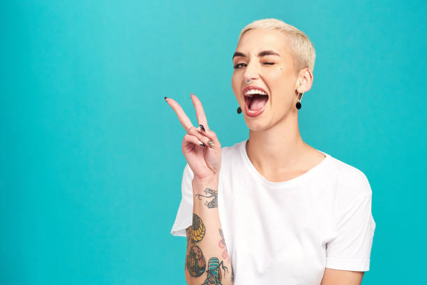 Fill the world with happiness Studio shot of a confident young woman making a peace gesture against a turquoise background punk person photos stock pictures, royalty-free photos & images