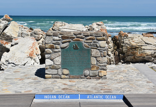 plaque at southernmost point of Africa against Atlantic Ocean and Indian Ocean at Cape Agulhas on sunny day