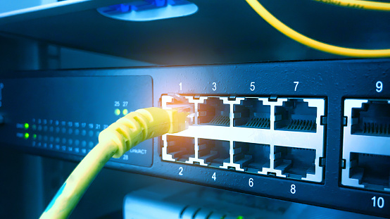 Interruptor de red y cable Ethernet en el fondo del gabinete del bastidor. Concepto de comunicación de red. Tono azul. photo