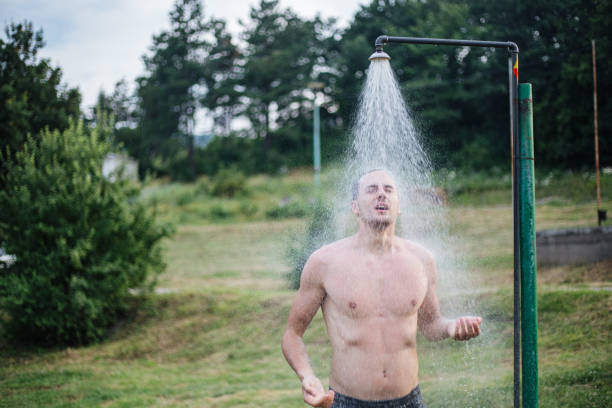 Pouring water out of a shower head placed on a grass area outdoors.
