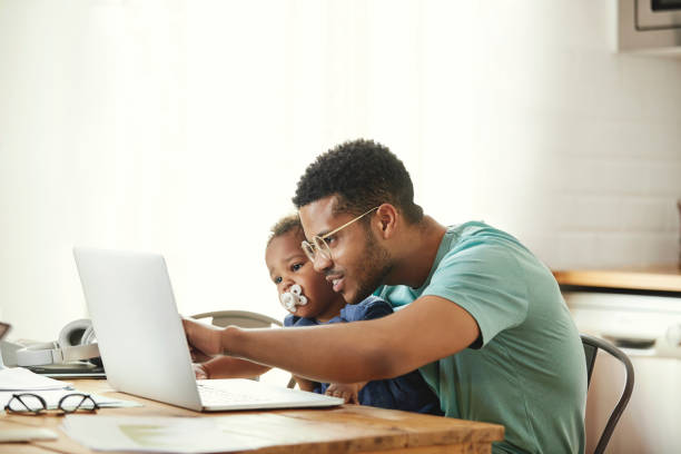 istock Smiling father showing laptop to son at table 1170309512
