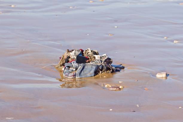 clothes and rubbish washed up onto sand beach by the atlantic ocean, agadir, morocco - toxic substance spilling pouring bottle imagens e fotografias de stock