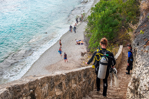 Scuba divers going down the stairs to the 1000 Steps dive site and beach, one of the great spots for diving and snorkeling in Bonaire, in the Caribbean Netherlands.
