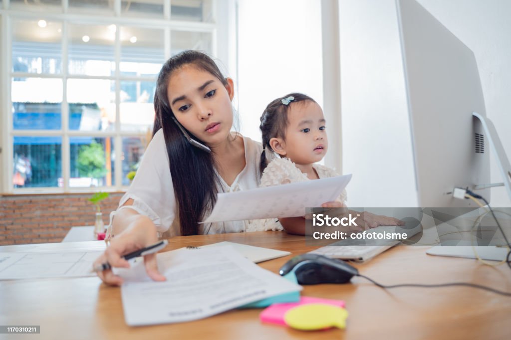 Working Parents at home,Busy Asian Woman mom working with Daughter at house Working Mother Stock Photo