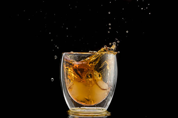 istock glass with whiskey and falling ice, splashes and drops 1170310941